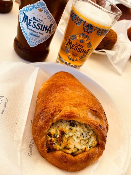 Ein Croissant mit Käsefüllung, eine Flasche Birra Messina Bier und ein Bierglas auf einem Tisch. 1