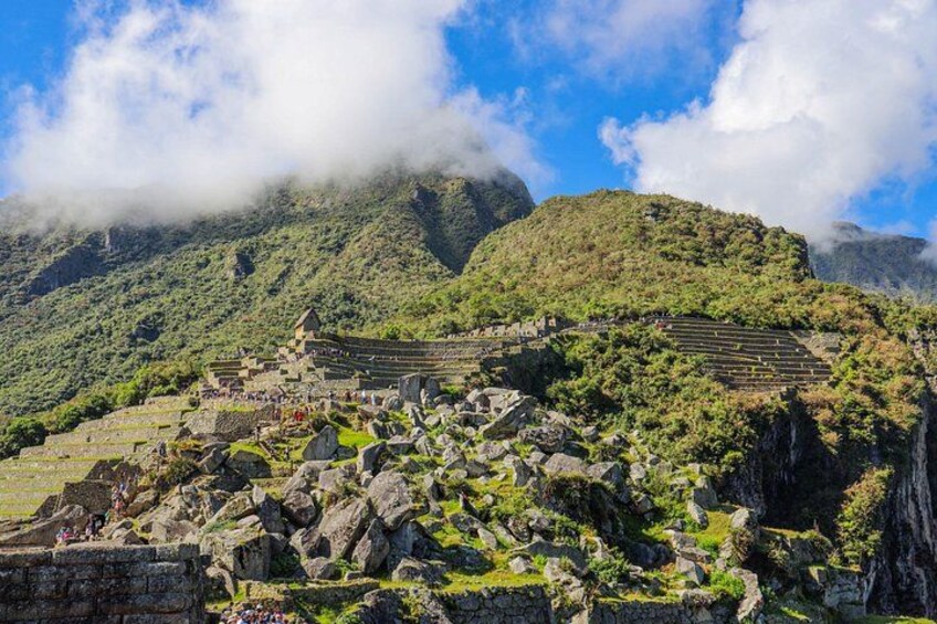 A historical site with ruins and terraced fields, surrounded by lush green mountains and clouds. 2