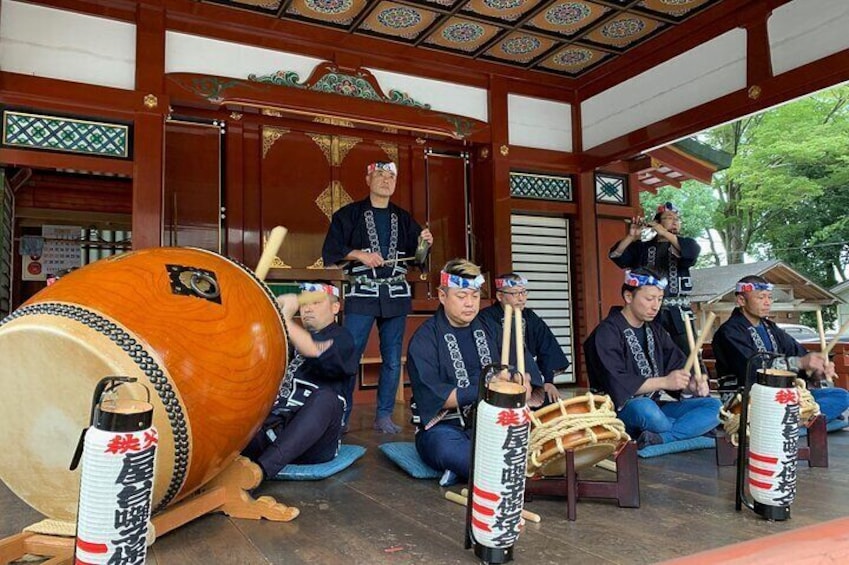 A group of musicians performing in a traditional setting with a large drum and smaller drums. 1