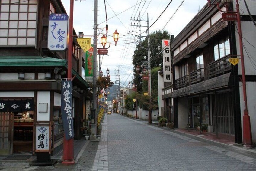 A narrow street lined with traditional buildings, some with signage in Japanese. 5