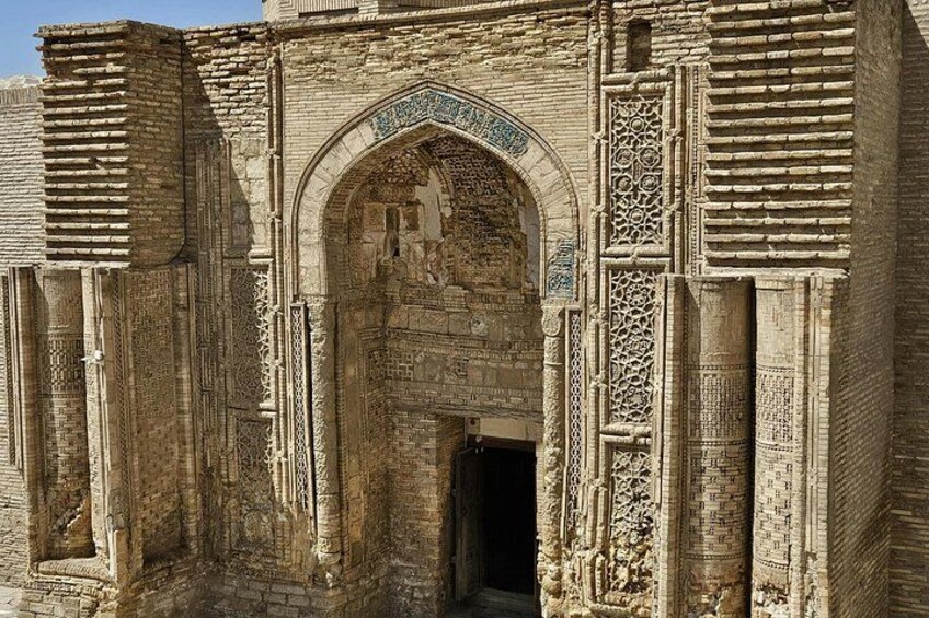 An ancient stone archway with intricate carvings and a small statue inside. 3