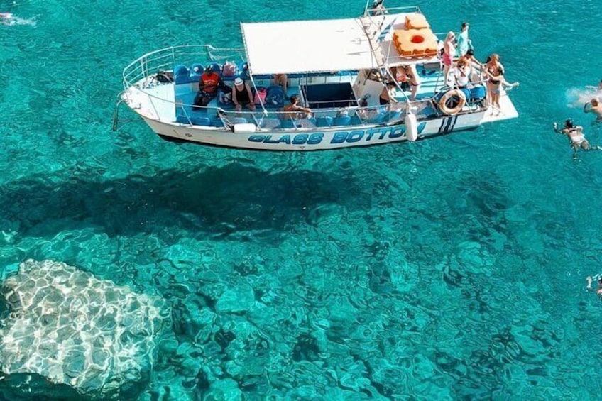 A boat named 'Glabz Botto' with people on board, floating on clear turquoise water. 1