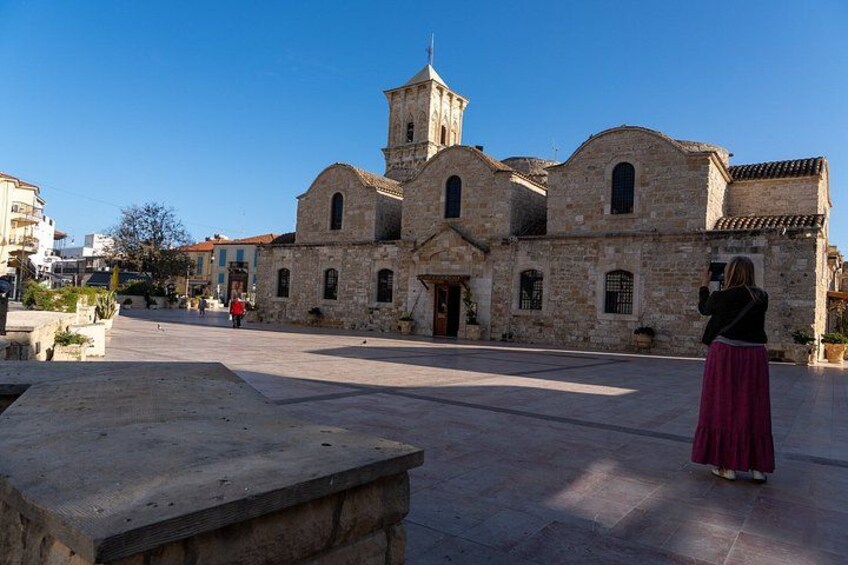Un edificio de piedra histórico con un campanario, una plaza empedrada y una persona tomando una fotografía. 3