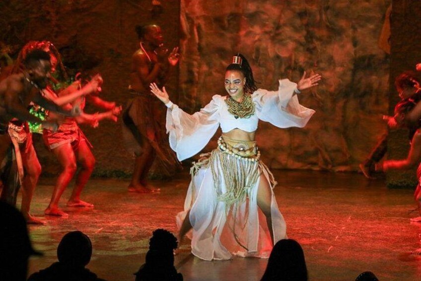 A dance performance with a central dancer in a white costume and others in red. 2