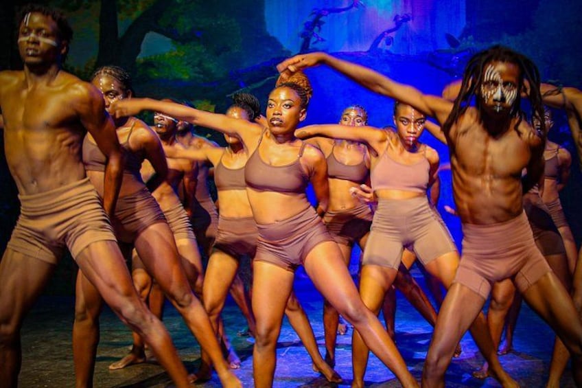 Un grupo de bailarines con vestuario a juego actuando en un escenario con un decorado de bosque. 4