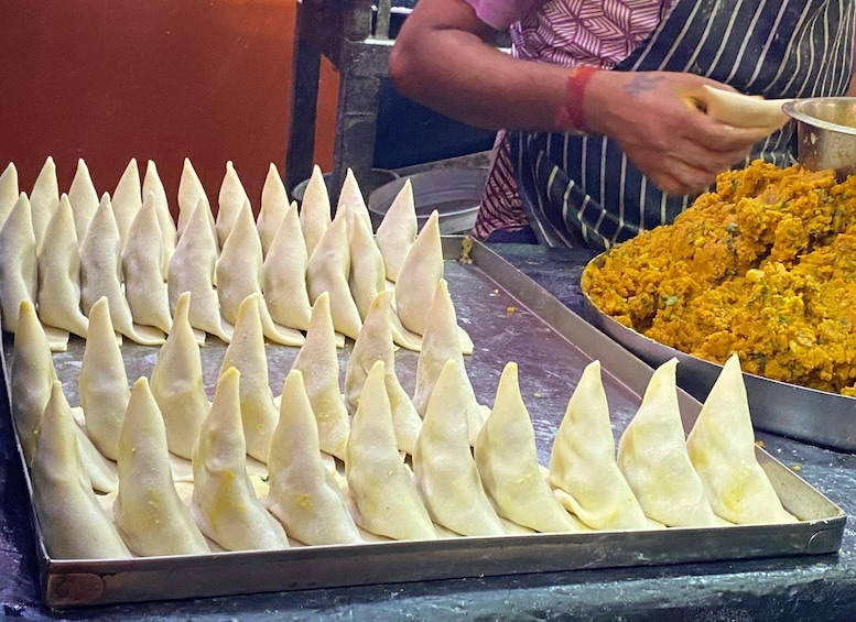 A tray of triangular-shaped pastries and a bowl of yellow food. 4