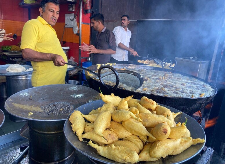 A street food vendor cooking at a large outdoor grill, with a variety of fried items on display. 2