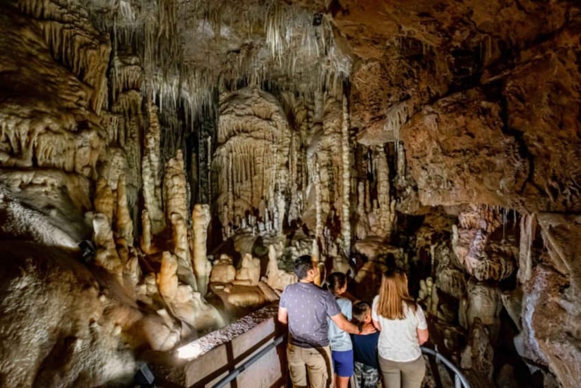 A group of people exploring a cave with stalactites and stalagmites. 4