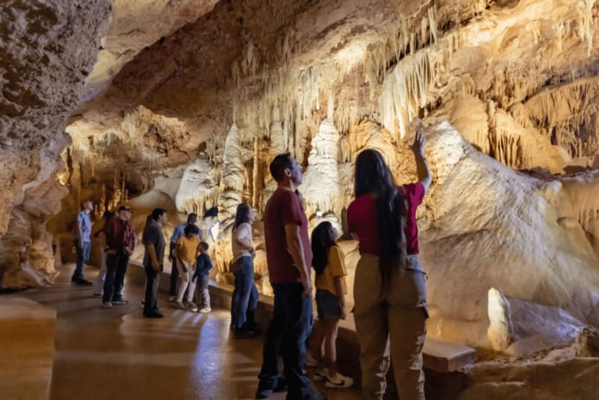 A group of people exploring a cave with stalactites and stalagmites. 3