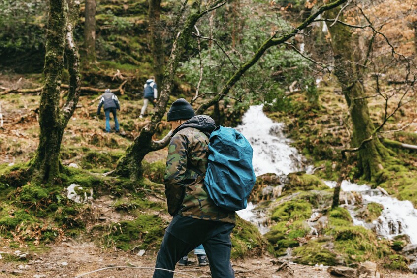 Un randonneur portant un sac à dos bleu marche sur un sentier de forêt. 2