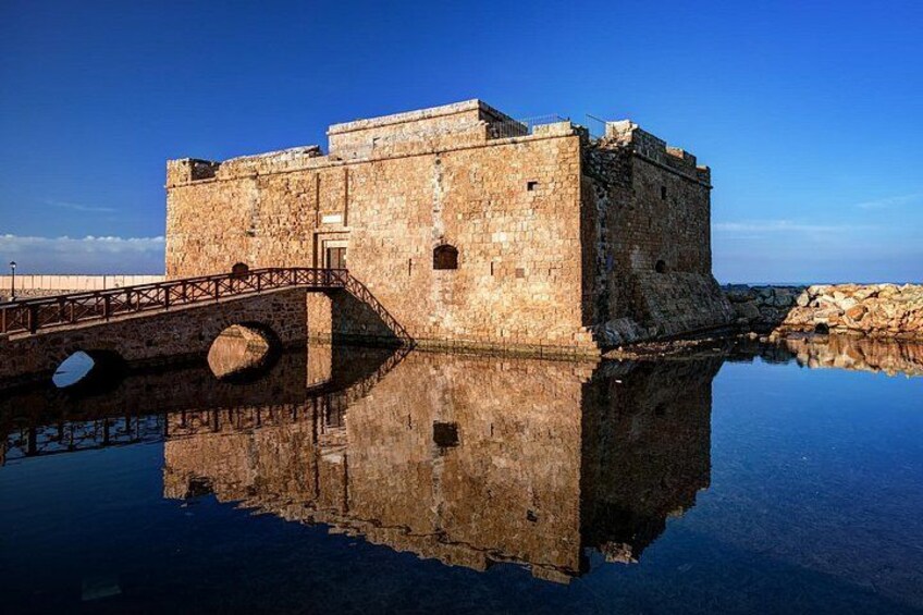 Eine steinerne Festung mit einer Brücke über dem Wasser, das sich in der ruhigen Oberfläche spiegelt. 4