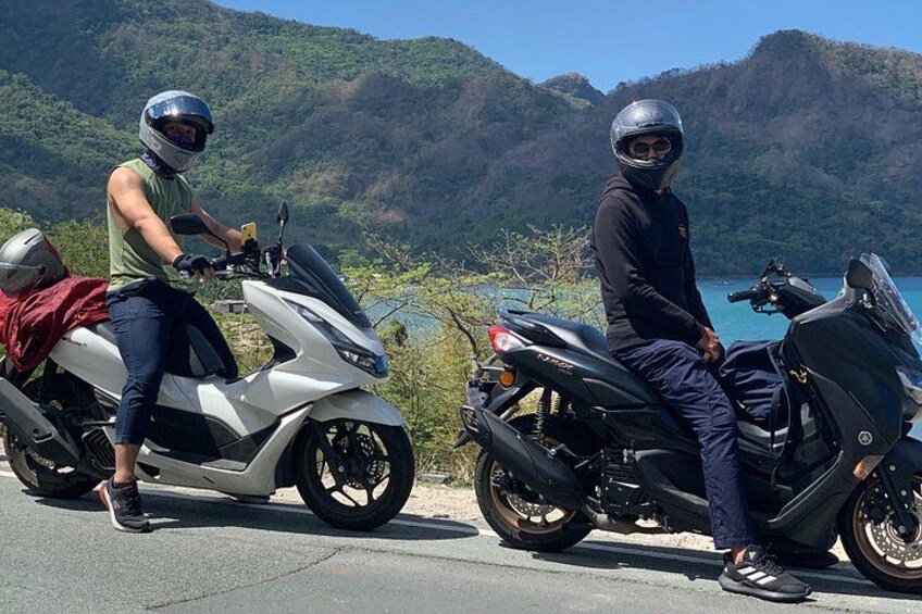 Two motorcycles parked on a road with a mountainous landscape in the background. 1