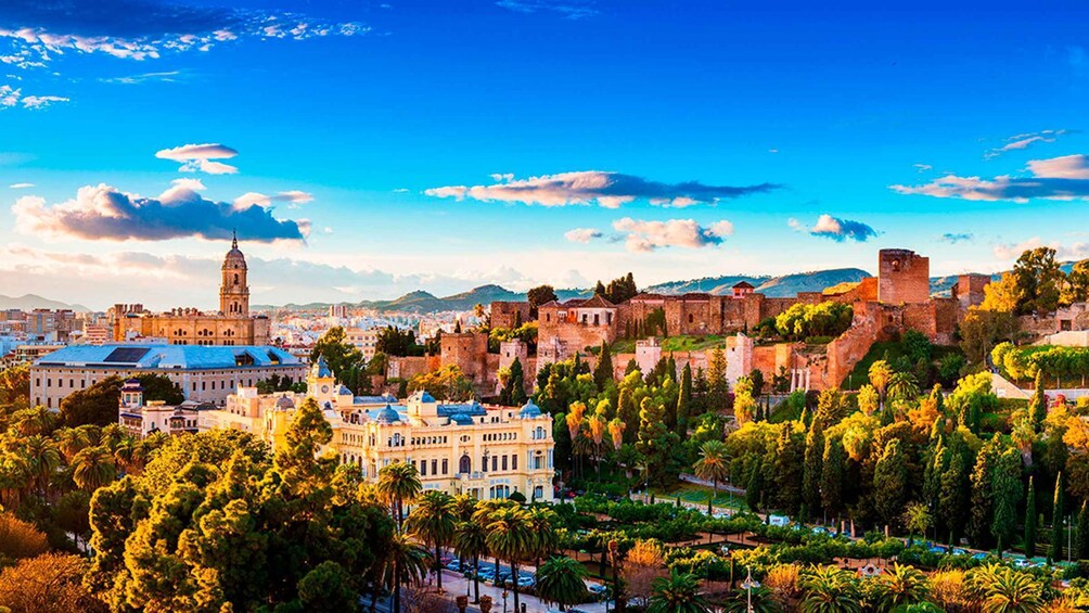 A historic cityscape with a prominent tower, lush greenery, and a fortified wall. 1