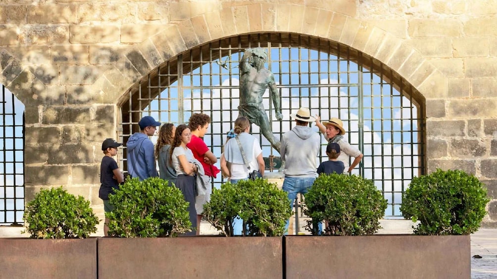 A group of people standing in front of a statue within an arched stone structure. 2