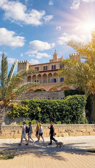 A historic building with a tower and arches, surrounded by palm trees and greenery. 3