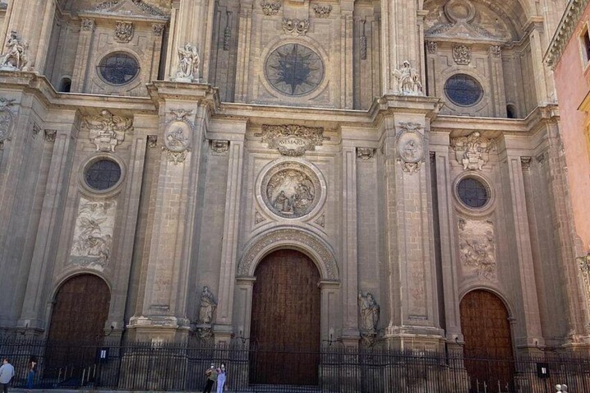 A grand historical building with ornate carvings, large wooden doors, and circular windows. 2