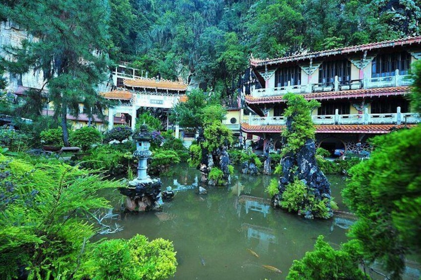 Een traditionele Chinese tuin met een vijver, rotsformaties en meerlaagse gebouwen. 1