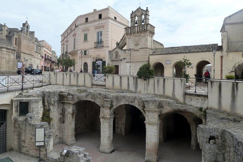 Un antico ponte in pietra con archi, un edificio storico con un campanile e un percorso pedonale lastricato. 4