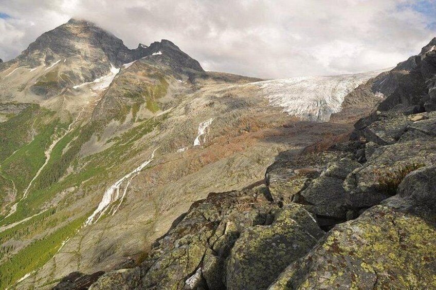 A mountain landscape with a glacier, rocky terrain, and a waterfall. 3