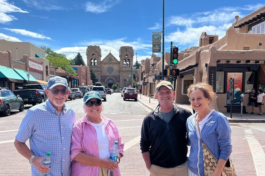 A group of people standing on a street with a church and buildings in the background. 4