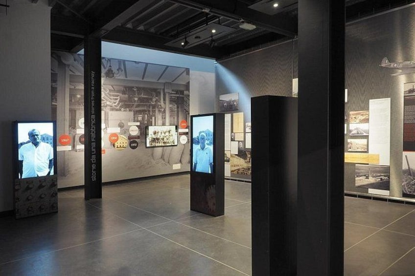 Een overdekte tentoonstellingsruimte met presentatiepanelen en grote schermen. 5
