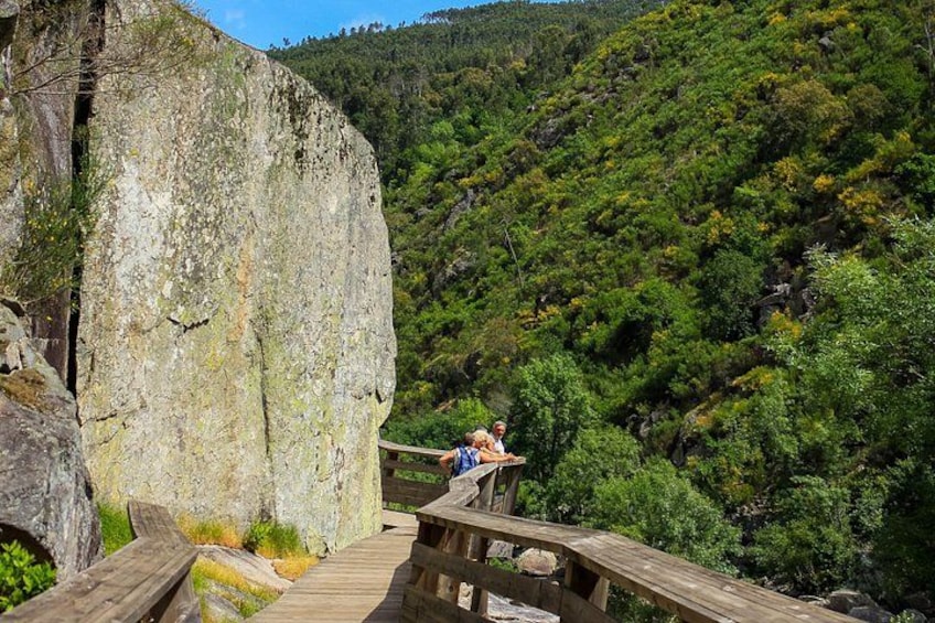 A wooden walkway with people on it, surrounded by a forested hillside. 4