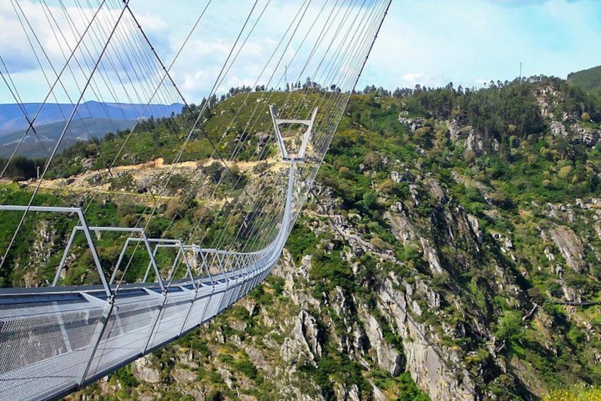 A suspension bridge over a rocky terrain with greenery. 1