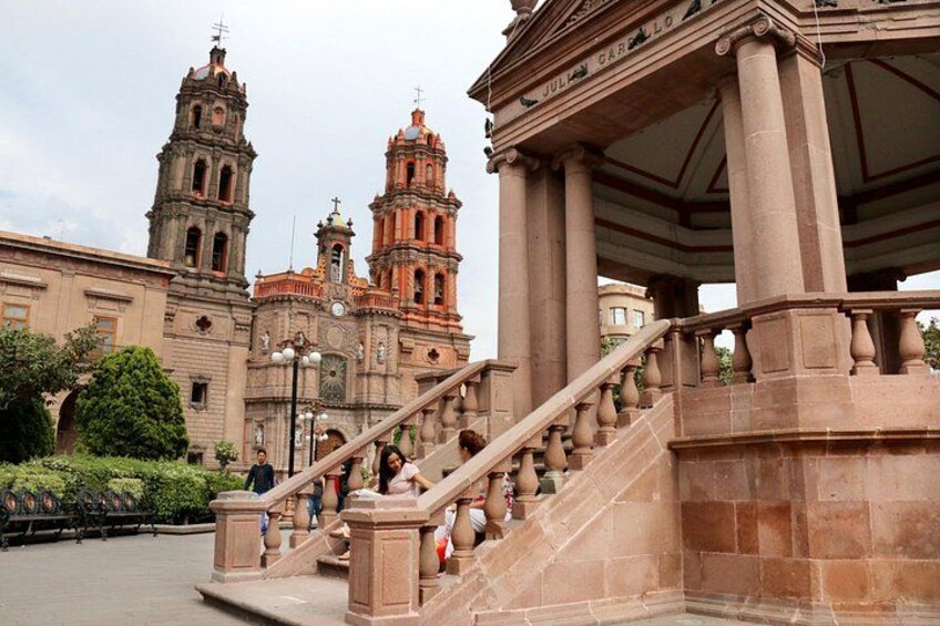 Una imponente escalera conduce a un edificio con dos torres destacadas, rodeado de follaje y un cielo despejado. 2