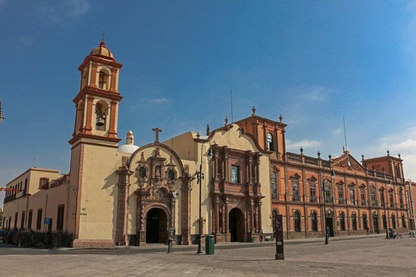 Un edificio histórico con una torre de campanas y entradas arqueadas. 5