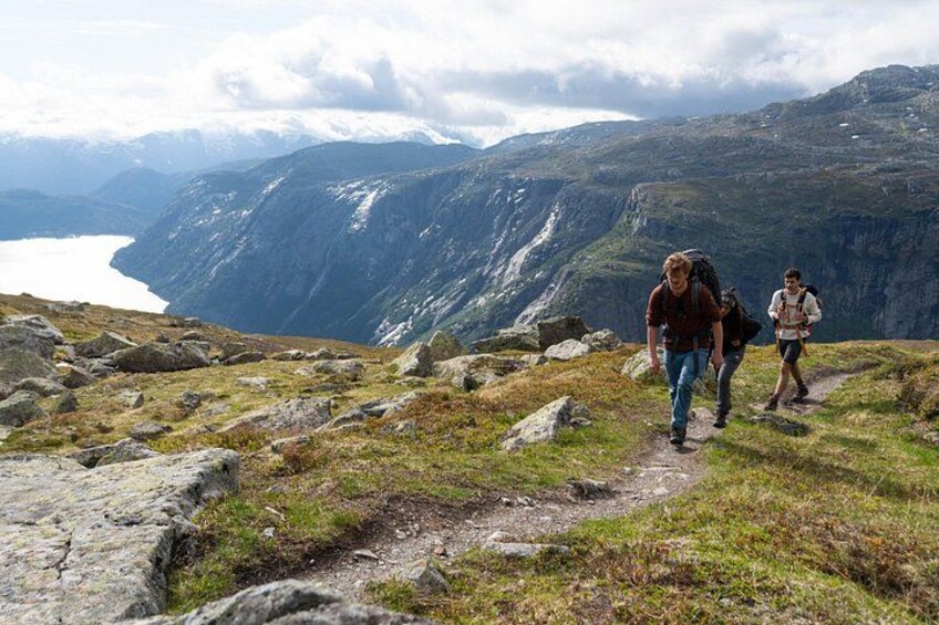 Wandelaars op een bergpad met een meer en bergen op de achtergrond. 2