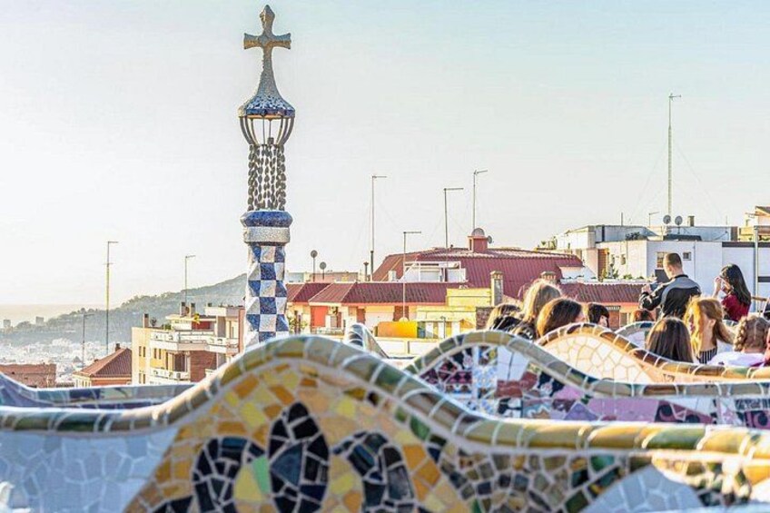 Ein mit Mosaikfliesen ausgelegter Weg, ein Turm mit Kreuz und Gebäude im Hintergrund. 3