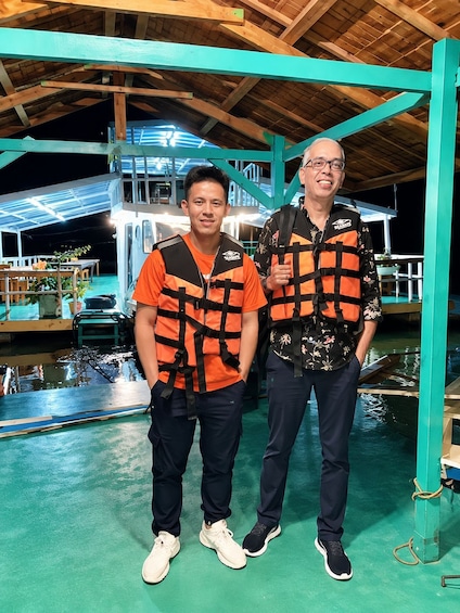 Two people wearing life jackets standing in a covered area with a pool. 5