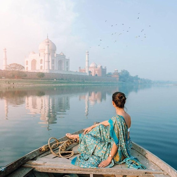 A person in a boat on a calm river with the Taj Mahal in the background. 5