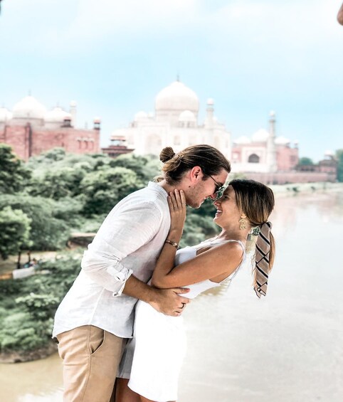 A couple embracing near a body of water with a large white-domed building in the background. 4