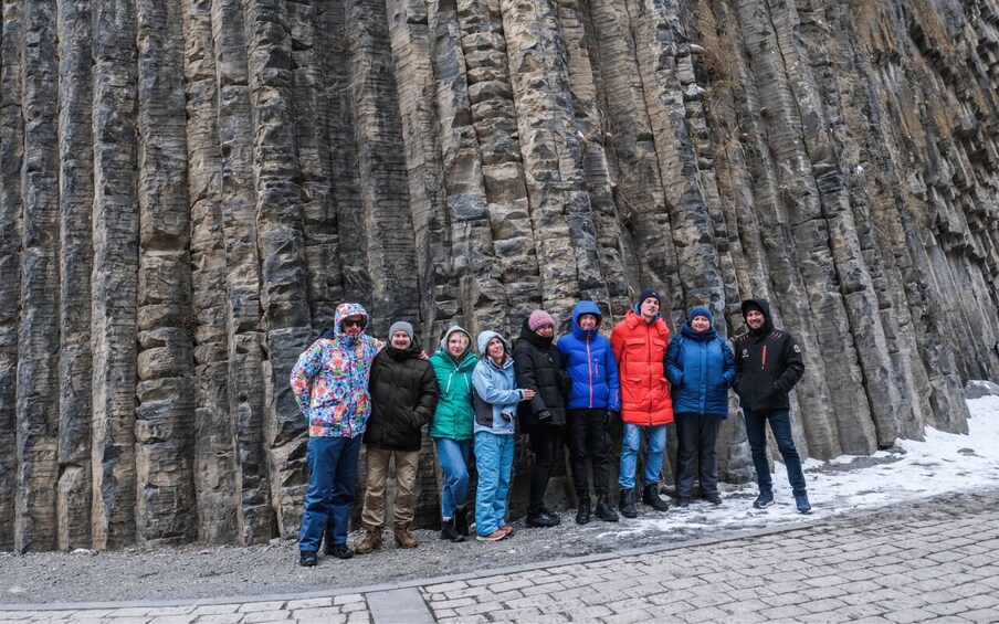 A group of people standing in front of a rocky cliff. 3