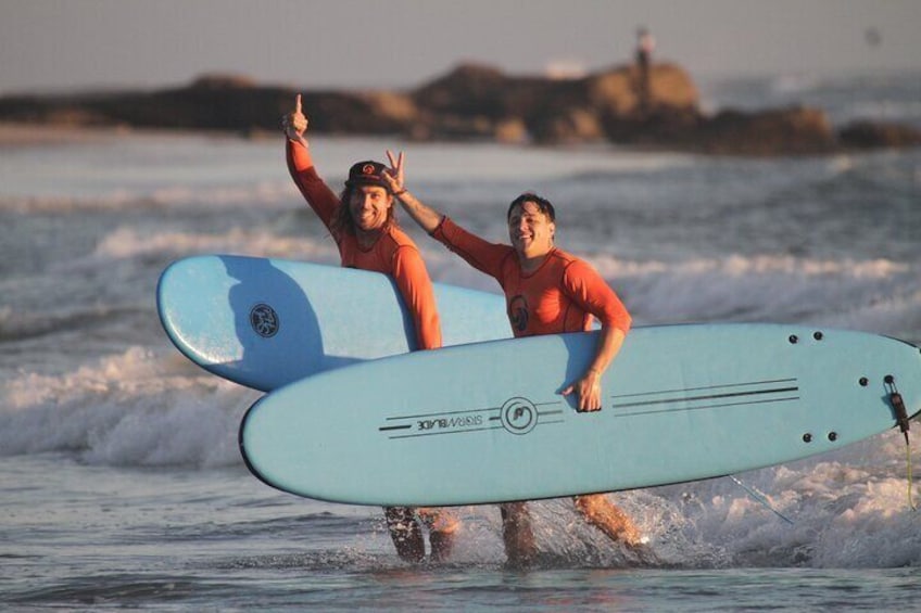 Two people walking in the water with surfboards. 4