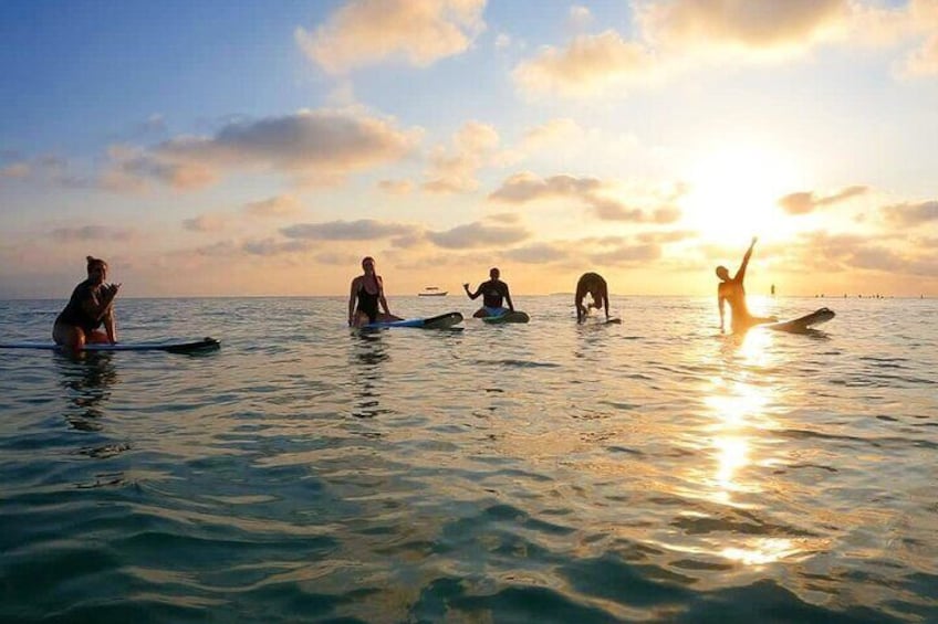 People on surfboards in the ocean at sunset. 1
