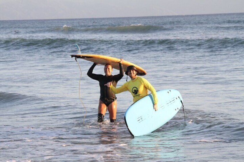 Two people carrying surfboards in the ocean. 1