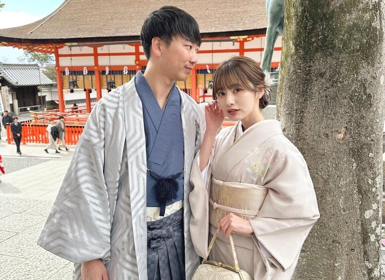 A man and a woman in traditional Japanese attire standing in front of a red torii gate. 1
