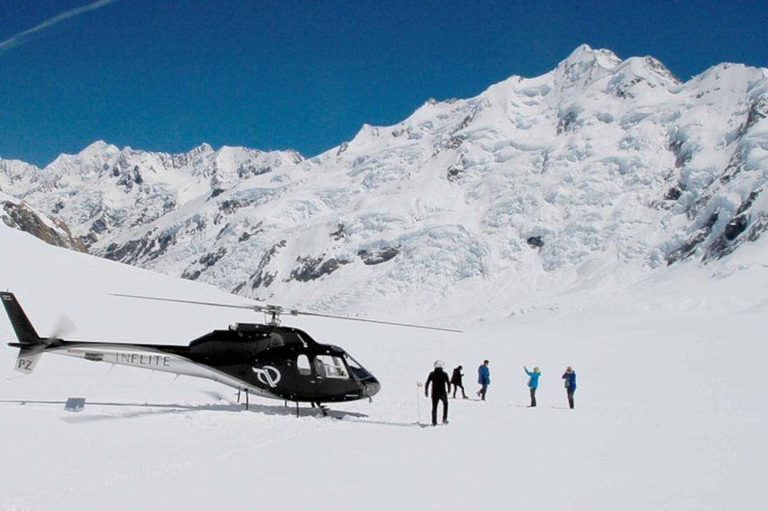A helicopter on a snowy mountain with people standing nearby. 2