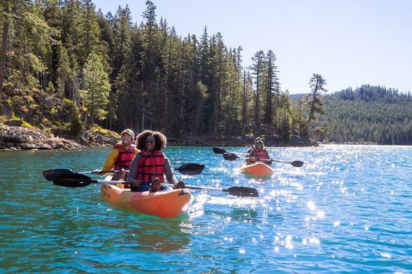 Personas haciendo kayak en un río tranquilo rodeado de un bosque frondoso. 5