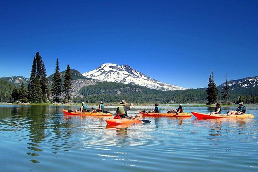 Personas haciendo kayak en un lago tranquilo con una montaña al fondo. 1