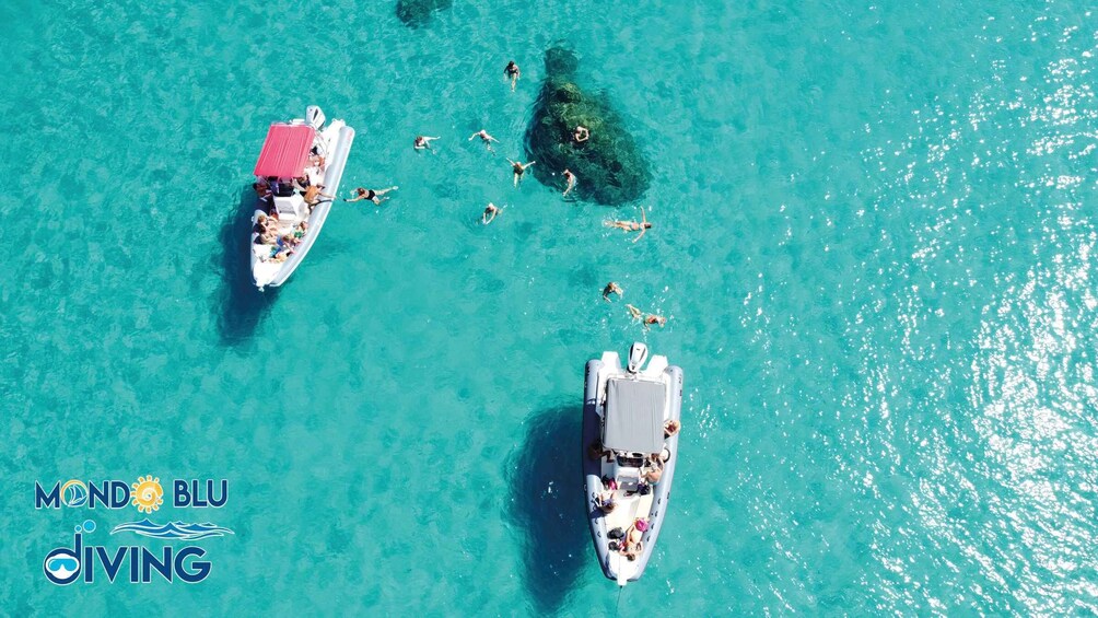 Two boats on turquoise water with people swimming and snorkeling. 1