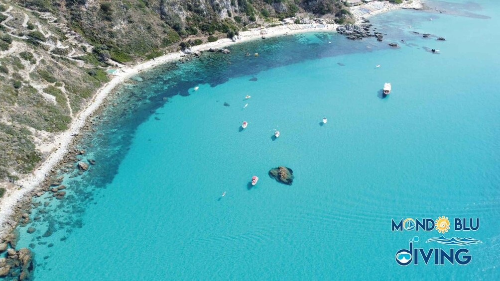 A coastal area with clear turquoise waters, rocky shorelines, and several boats. 5