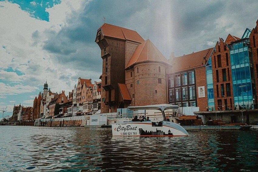 A historic building with a tower, a modern glass structure, and a boat named 'CityBoat' on the water. 2