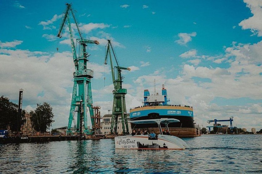 A large cargo ship docked at a port with cranes and a smaller boat nearby. 2