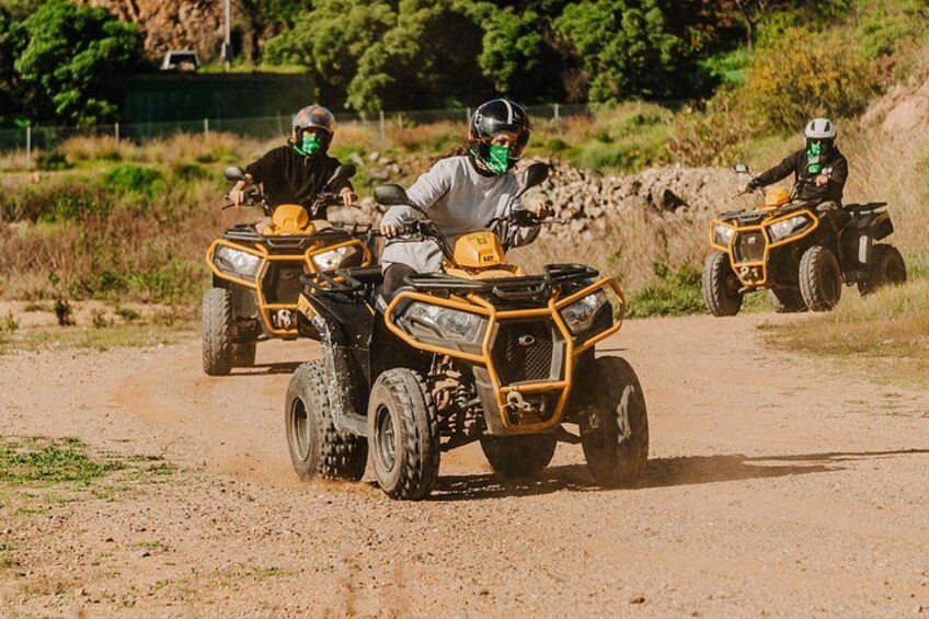 Tres personas paseando en cuatrimotos por un sendero de tierra. 2