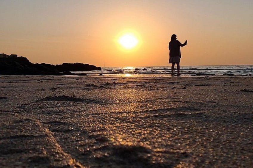 Une personne se tient sur une plage au coucher du soleil. 1