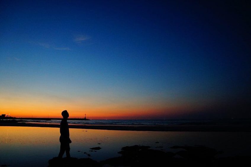 La silhouette d’une personne se tenant sur une plage au coucher du soleil. 2