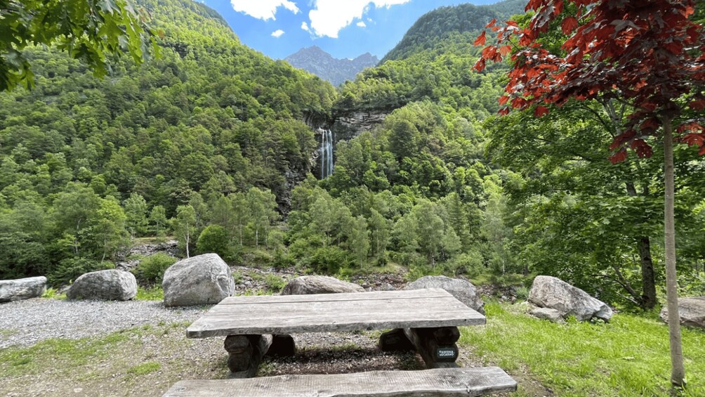 A picnic table in a forested area with a waterfall in the background. 5